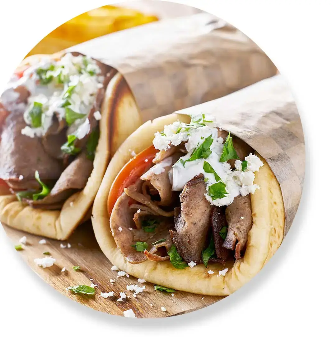 Two gyros wrapped in paper, filled with meat, tomatoes, lettuce, feta cheese, and topped with sauce. Two gyros wrapped in paper, filled with meat, tomatoes, lettuce, feta cheese, and topped with sauce.